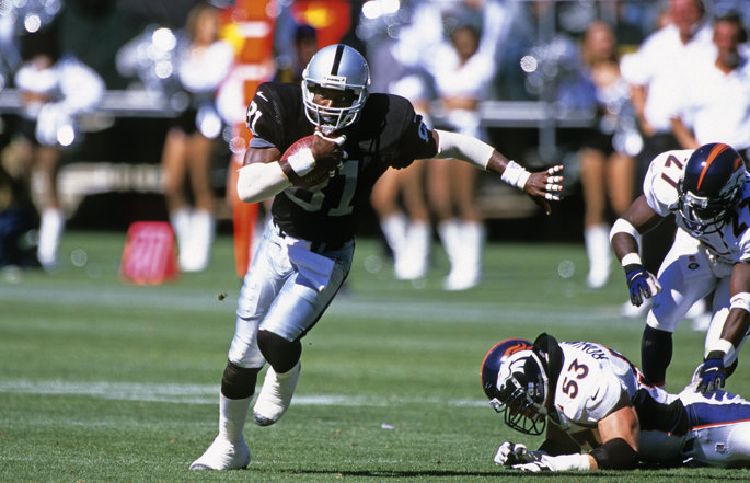 Former Las Vegas Raiders wide receiver Tim Brown runs with the football.