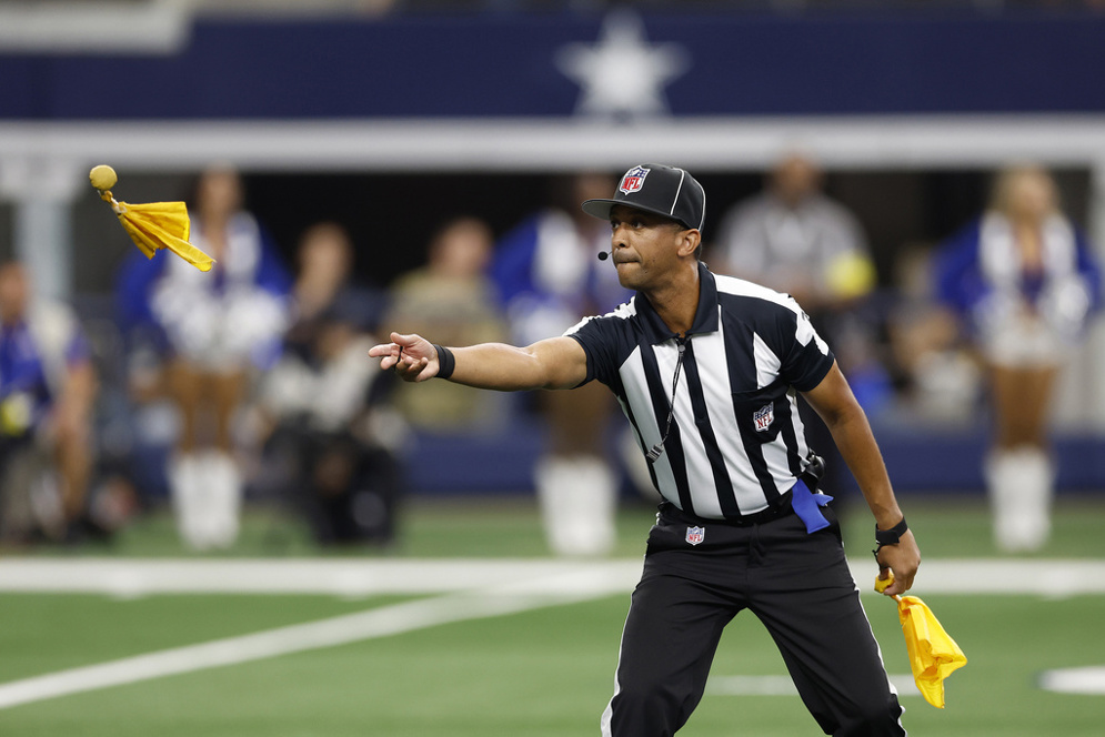 NFL official Scott Walker tosses a penalty flag to another NFL official during an NFL game (AP/James D. Smith)
